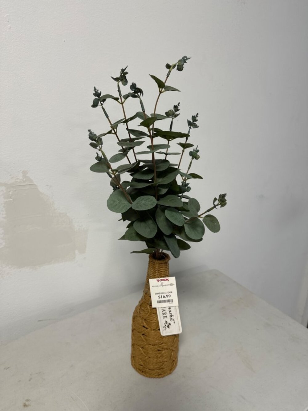 Arreglo decorativo artificial de eucalipto en tonos verde oscuro, colocado en un